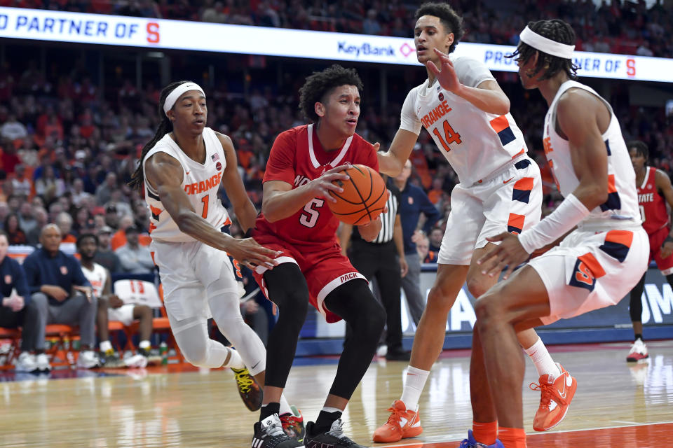North Carolina State guard Jack Clark (5) is defended by Syracuse forward Maliq Brown (1), center Jesse Edwards (14) and forward Chris Bell (0) during the first half of an NCAA college basketball game in Syracuse, N.Y., Tuesday, Feb. 14, 2023. (AP Photo/Adrian Kraus)