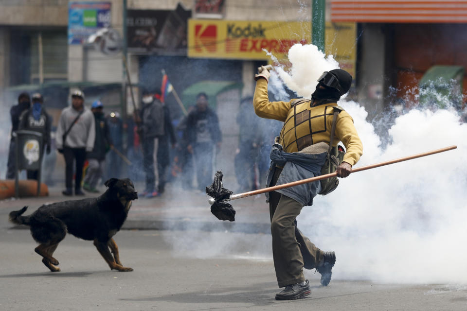 A backer of former President Evo Morales returns a tear gas canister to police during clashes in La Paz, Bolivia, Wednesday, Nov. 13, 2019. Bolivia's new interim president Jeanine Anez faces the challenge of stabilizing the nation and organizing national elections within three months at a time of political disputes that pushed Morales to fly off to self-exile in Mexico after 14 years in power. (AP Photo/Natacha Pisarenko)