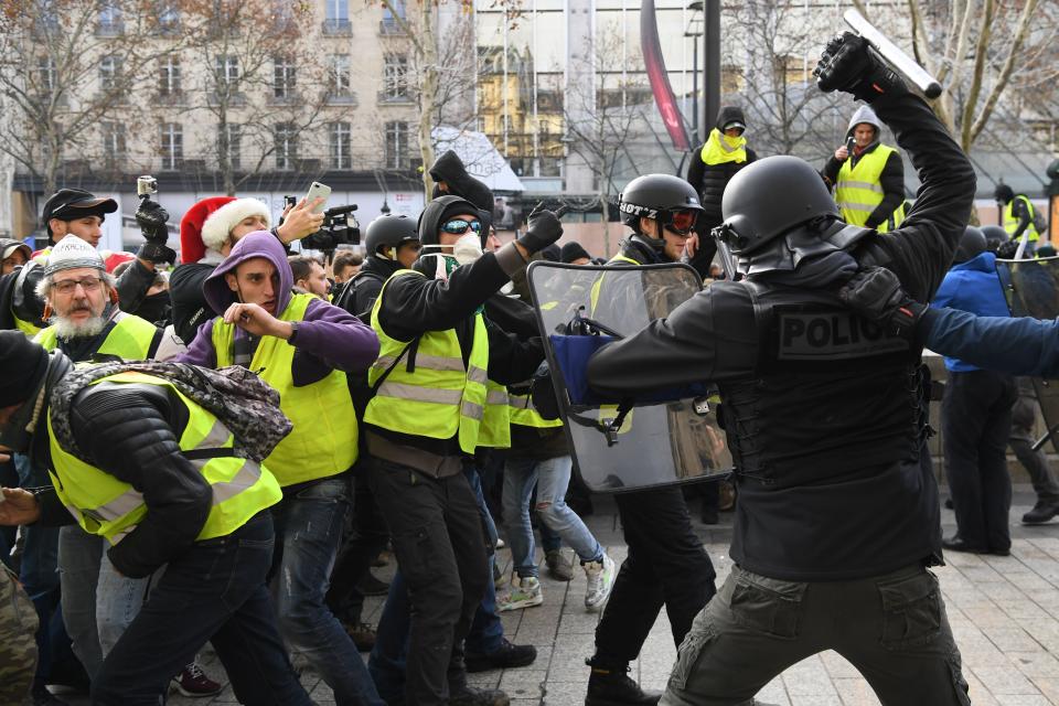 Riot police clash with men wearing “yellow vests” (gilets jaunes) protestors on Dec. 8, 2018 near the Arc de Triomphe in Paris during a protest against rising costs of living they blame on high taxes. (Photo: Alain Jocard/AFP/Getty Images)