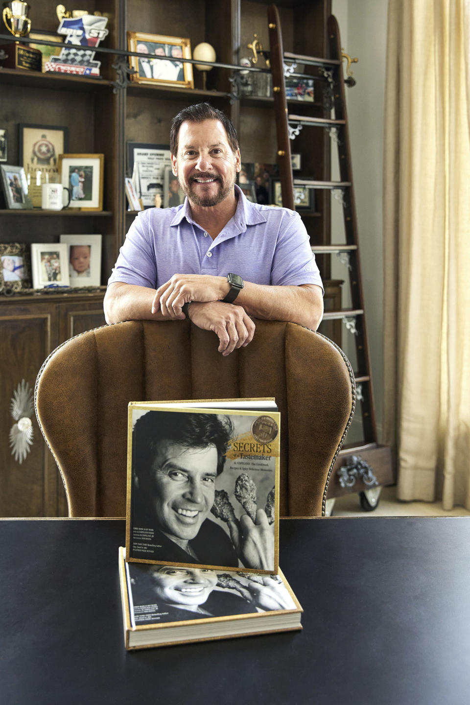 This photo provided by Foxglove Communications shows posing . Al Copeland Jr. with his cookbook “Secrets of a Tastemaker: Al Copeland, The Cookbook.” Louisiana is known for delivering food with big, bold flavor. The same can be said for the founder of the Popeyes fried chicken empire who put spicy chicken, red beans and dirty rice on the map and whose story is outlined in a new book _ “Secrets of a Tastemaker: Al Copeland, The Cookbook.” Copeland's son, Al Copeland Jr., said he and the book's authors, Chris Rose and Kit Wohl, tried to capture the “real life and times of Al Copeland." (Sam Hanna/Foxglove Communications via AP)