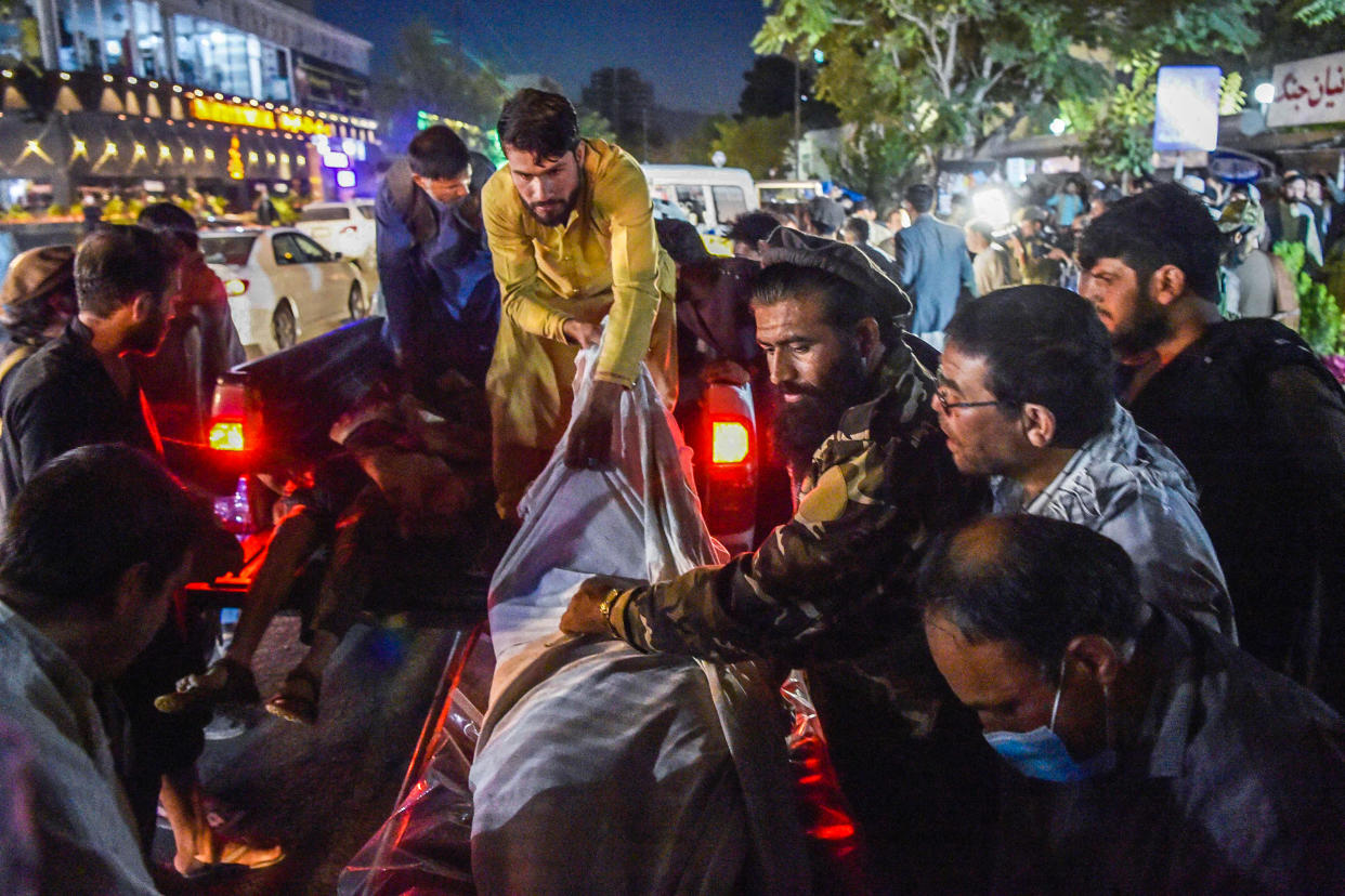 Image: Volunteers and medical staff unload bodies from a pickup truck outside a hospital after two powerful explosions, which killed at least six people, outside the airport in Kabul on Aug. 26, 2021. (Wakil Kohsar / AFP - Getty Images)