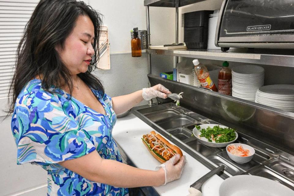 Leila Jace, owner of Sizzle n’ Steam in central Fresno, prepares a chili lemongrass tofu sandwich at the restaurant on Monday, June 5, 2023. Vietnamese bánh mì-style sandwiches are served on toasted French baguettes dressed with pate, mayonnaise, cucumber, cilantro and pickled carrot, daikon and jalapeño.