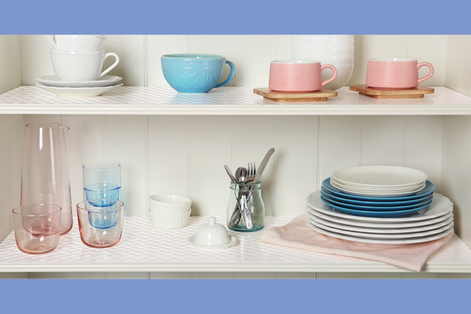 the clear shelf liners in a cabinet with mugs, dishes and glasses