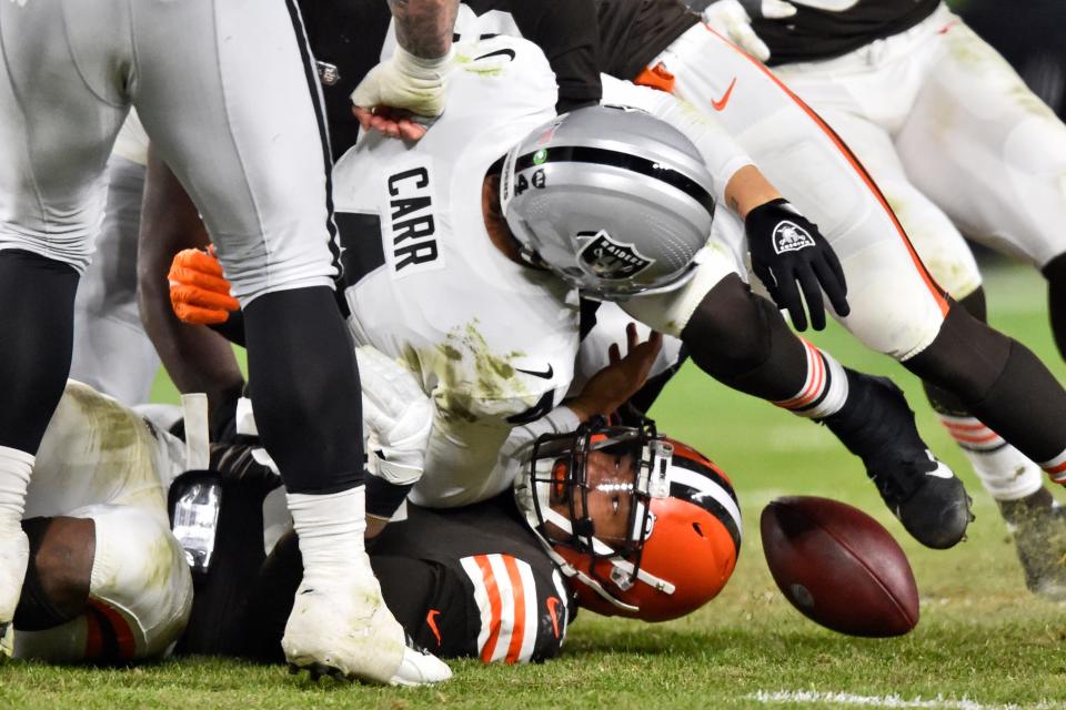 Las Vegas Raiders quarterback Derek Carr, top, is sacked by Cleveland Browns defensive end Myles Garrett, bottom, during the second half of an NFL football game, Monday, Dec. 20, 2021, in Cleveland. (AP Photo/David Richard)