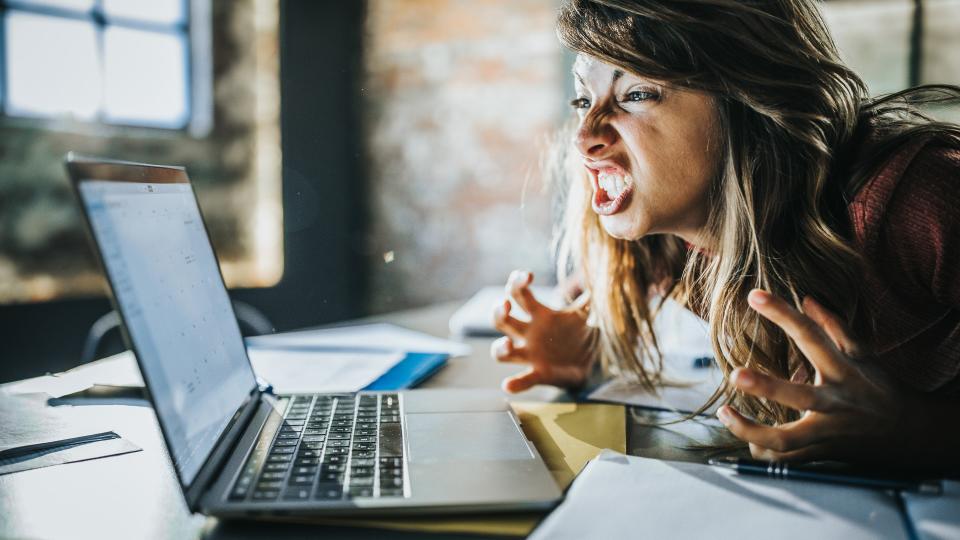 Angry freelance worker feeling displeased after reading an e-mail on a computer.