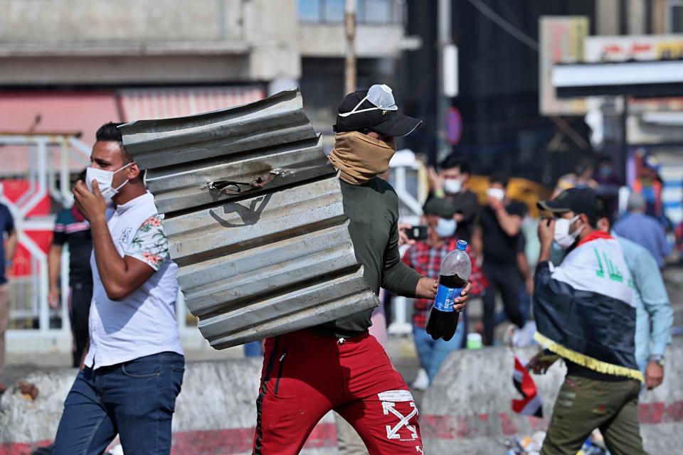 An anti-government protester uses a piece of tin as a shield during a demonstration in Tahrir Square, Baghdad, Iraq, Sunday, Oct. 27, 2019. Protests have resumed in Iraq after a wave of anti-government protests earlier this month were violently put down. At least 149 people were killed in a week of demonstrations earlier in October. (AP Photo/Hadi Mizban)