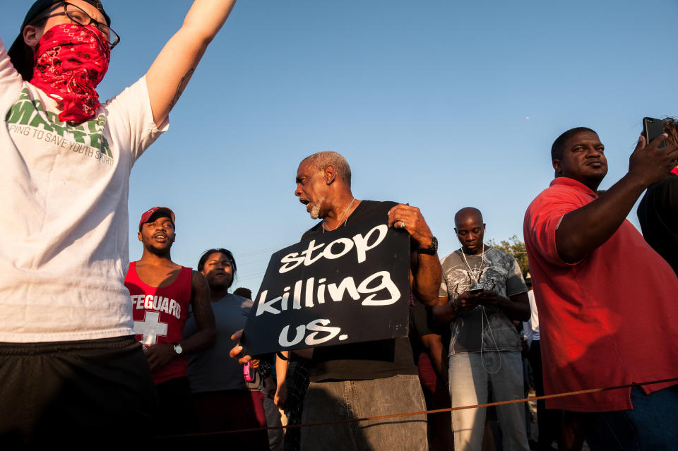 Protesters hold signs as police block their way near the St. Louis Galleria.