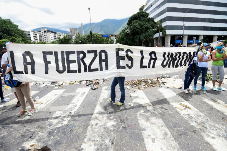 Opposition activists hold a banner reading, "The Strength is the Union" as they demonstrate against President Nicolas Maduro's government in Caracas