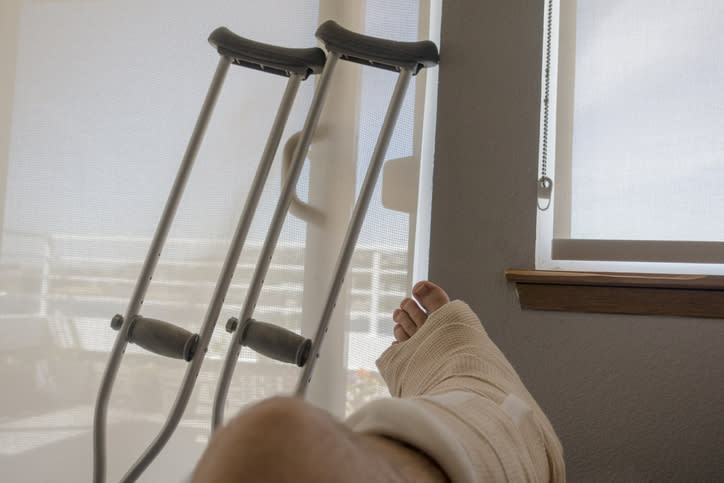 Crutches leaning on a door as someone's foot appears to be broken