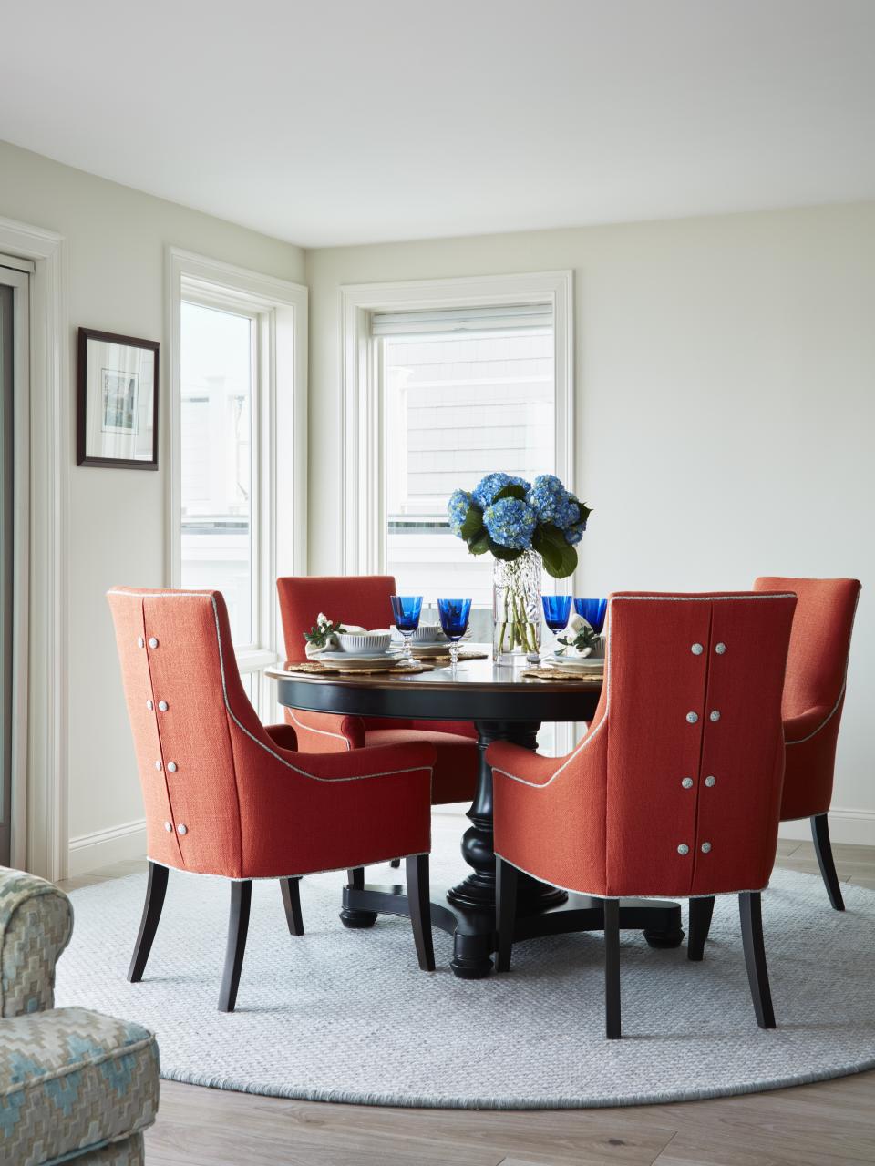 This image provided by Susan Hayward Interiors shows dining chairs. "The orange dining chairs in this airy waterfront dining room are from Kravet," says Designer Jillian Hayward Schaible of Susan Hayward interiors. She says you can spend less on small furnishings and accessories, but it's worth investing in the pieces that you sit, sleep and eat on. They tend to have longevity and be more comfortable. (Jared Kuzia via AP)