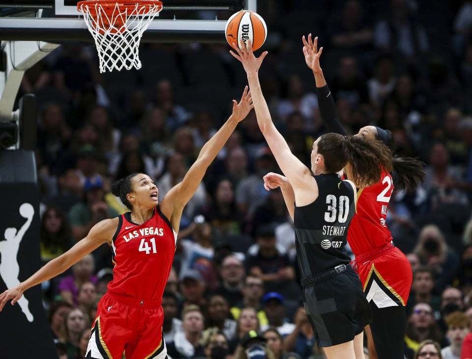 Seattle Storm forward Breanna Stewart (30) makes a shot between Las Vegas Aces center Kiah Stokes (41) and Aces forward A'ja Wilson, right, during the second half of Game 4 of a WNBA basketball playoff semifinal Tuesday, Sept. 6, 2022, in Seattle. The Aces beat the Storm 97-92 to advance to the WNBA Finals. (AP Photo/Lindsey Wasson)