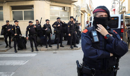 A Mosso d'Esquadra, Catalan regional police officer, stands guard in front of Spanish National Police officers as they wait to get into police vehicles in front of their hotel in Pineda de Mar, north of Barcelona, Spain, October 3, 2017. REUTERS/Albert Gea