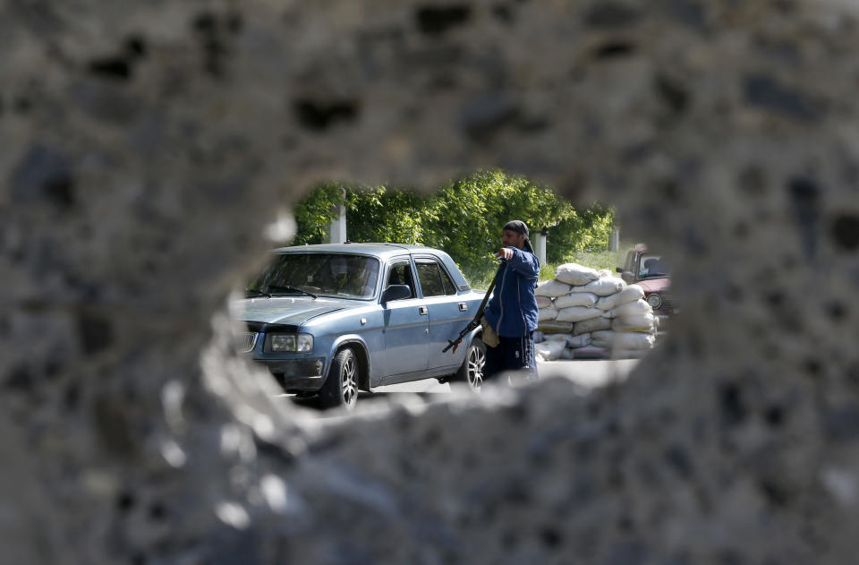 An armed pro-Russian man checks a car at the barricades on a road leading into Slovyansk, eastern Ukraine, Tuesday, May 13, 2014. Pro-Russian insurgents, who have seized government buildings and clashed with government forces during the past month, held Sunday's referendum, which Ukraine's acting president called a "sham" and Western governments said violated international law. (AP Photo/Darko Vojinovic)