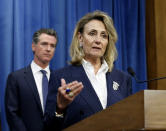 FILE - In this July 23, 2019, file photo, Marybel Batjer, of the California Public Utilities Commission, speaks during a news conference as Gov. Gavin Newsom looks on in Sacramento, Calif. California's utility regulator is issuing a series of sanctions against Pacific Gas and Electric for what it calls "failures in execution" during the largest planned power shut-off in state history to avoid wildfires. Batjer said Monday, Oct. 14, 2019, the utility needs to have a goal of restoring power within 12 hours instead of its current 48 hours, minimize the scale of future outages and better communicate with the public and local officials. (AP Photo/Rich Pedroncelli, File)