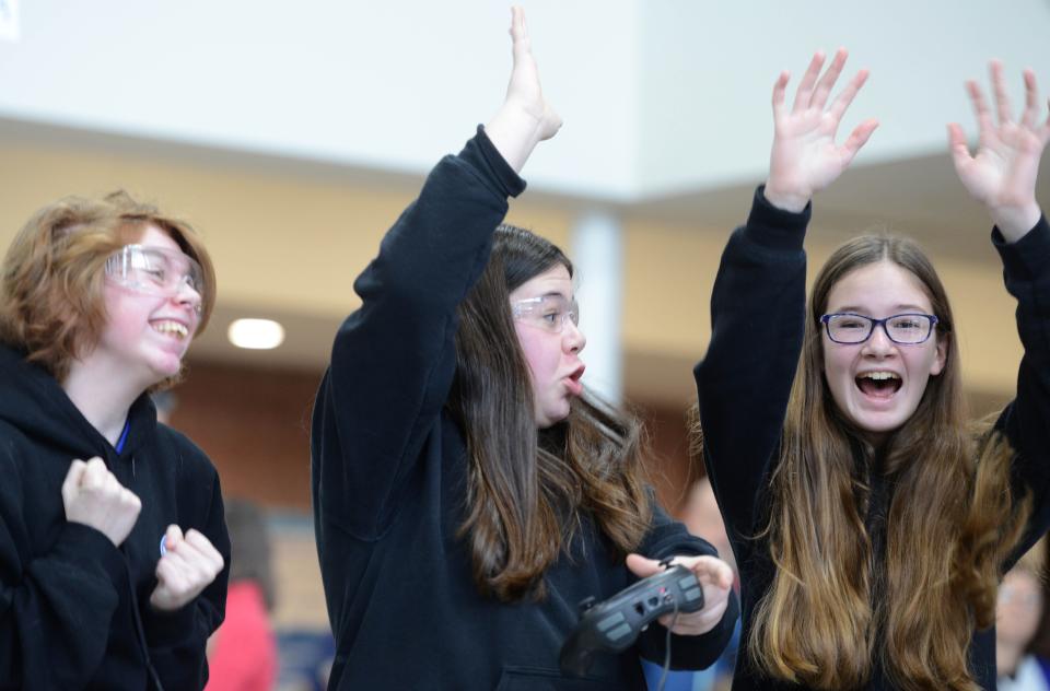 Mashpee Middle-High School eight-grader Max Nash, left, eighth-grader Sophia Saviano, center with controller, seventh-grader Esme Milde, celebrate a win in the ring Saturday at the school during a regional robotics competition on Saturday.