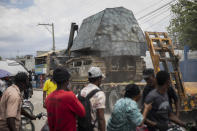 Residents watch as an armored police car is transported on the bed of a trailer, to be used in an anti-gang operation in Croix-des-Missions, north of Port-au-Prince, Haiti, Thursday, April 28, 2022. Prime Minister Ariel Henry has remained largely quiet amid the escalating gang violence, while Haiti's new police chief pledged in a May 9 news conference to, "continue to track down the criminals." (AP Photo/Odelyn Joseph)