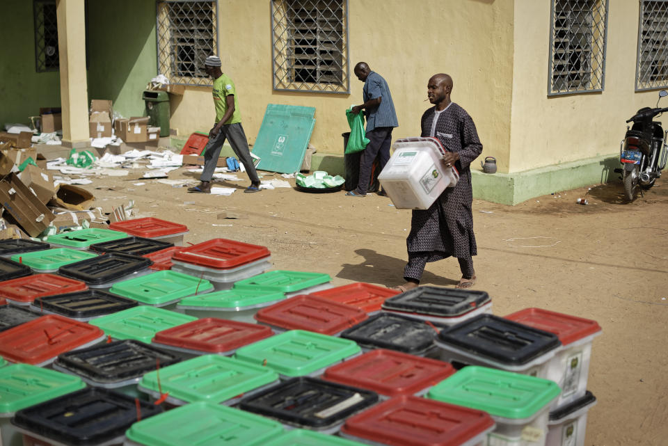 An electoral worker carries and stacks ballot boxes at an electoral commission office in Kano, in northern Nigeria Sunday, Feb. 24, 2019. Vote counting continued Sunday as Nigerians awaited the outcome of a presidential poll seen as a tight race between the president and a former vice president. (AP Photo/Ben Curtis)