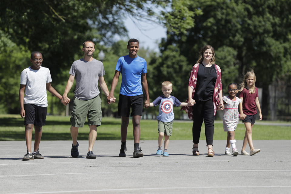 Paul and Cindy Neal walk with their children, from left, Musse, Belachew, Elisha, Edile and Miriam at Garfield Park, Sunday, June 14, 2020, in Indianapolis. The Associated Press discussed race with six white couples who have adopted or have custody of Black children. These parents are trying to help their children understand race in America while getting an accelerated course themselves. (AP Photo/Darron Cummings)