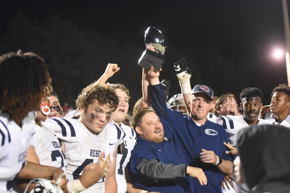 Effingham County head coach John Ford and team hoist the coveted County Trophy after the game, a 34-0 win over host South Effingham on Sept. 24 in Guyton.