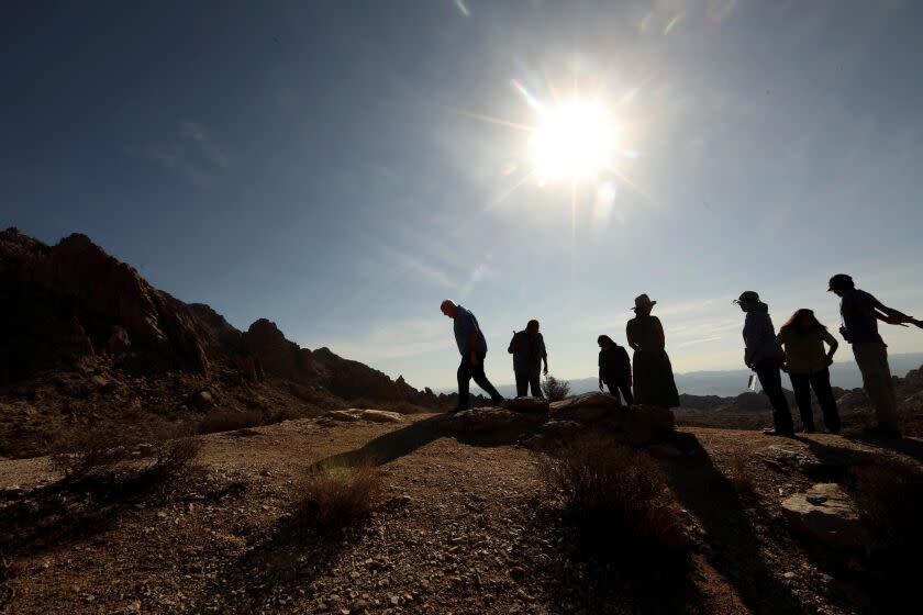 SEARCHLIGHT, NEVADA - JULY 31, 2022 - - Allen O'Neill, a retired superintendent of Lake Mead National Recreation Area, from left, Paul Jackson, an artist and spokesman for the Fort Mojave Indian Tribe, Nora McDowell, a member of the Fort Mojave Tribe, Kim Garrison Means, artist and owner of The Mystery Ranch, biologist Michael Webber, Linda Otero, a Fort Mojave Indian Tribe leader and Neal Desai, with the National Parks Conservation Association, stand at the foot of Spirit Mountain or Avi Kwa Ame being considered for National Monument status, just south of Searchlight, Nevada on August 31, 2022. Spirit Mountain is listed on the United States National Register of Historic Places as a sacred place to Native American tribes in Southern Nevada. (Genaro Molina / Los Angeles Times)