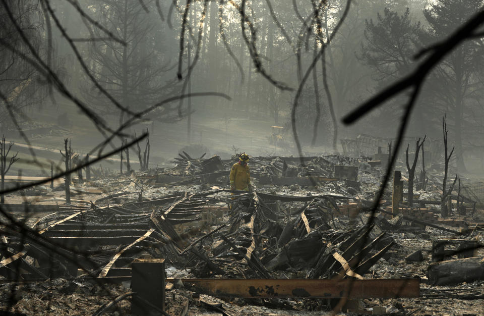 FILE - A firefighter searches for human remains in a trailer park destroyed in the Camp Fire on Nov. 16, 2018, in Paradise, Calif. The Camp Fire bears many similarities to the deadly wildfire in Hawaii. Both fires moved so quickly residents had little time to escape. (AP Photo/John Locher, File)