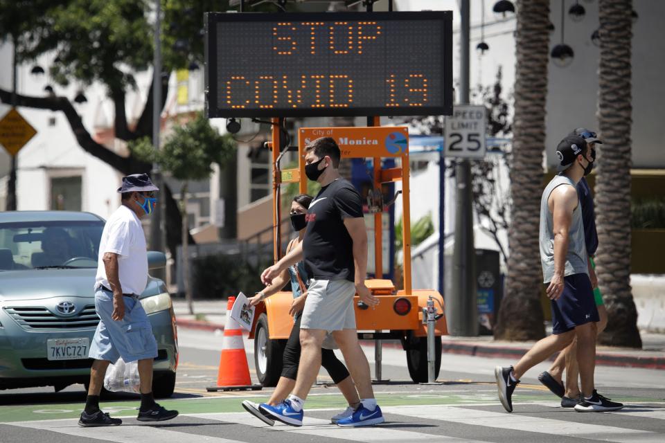 Pedestrians wear masks as they cross a street amid the coronavirus pandemic in Santa Monica, California, which has registered the highest number of COVID-19 cases in the U.S.