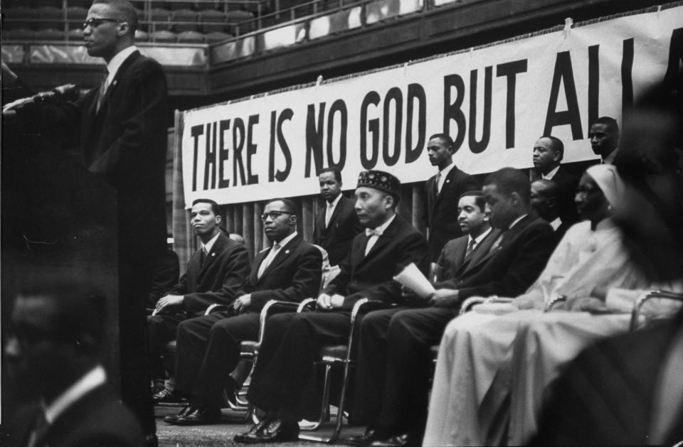 Nation of Islam leader Elijah Muhammad listens to Malcolm X speak in 1961.