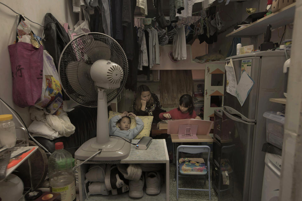 <p>Li Suet-wen and her son, 6, and daughter, 8, live in a 120-square-foot room crammed with a bunk bed, small couch, refrigerator, washing machine and small table, in an aging walkup in Hong Kong that she pays $580 per month for in rent and utilities. That’s nearly half the $1,290 she earns monthly at a bakery decorating cakes. (Photo: Kin Cheung/AP) </p>