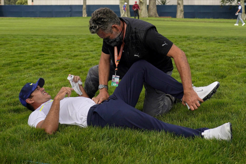 File-This Aug. 7, 2020, file photo shows Brooks Koepka getting treated for an injury on the 12th hole during the second round of the PGA Championship golf tournament at TPC Harding Park Friday, Aug. 7, 2020, in San Francisco. Koepka was out two months with a hip injury and returns this week at the CJ Cup at Shadow Creek in Las Vegas. (AP Photo/Jeff Chiu, File)