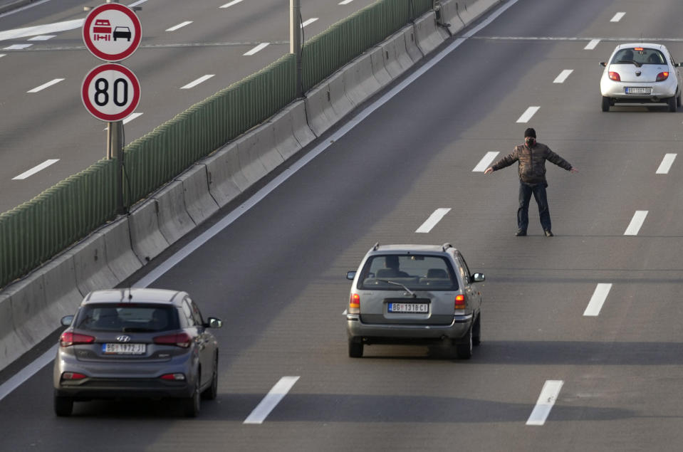 A protester stands on the highway during protest in Belgrade, Serbia, Saturday, Dec. 4, 2021. Protesters blocked roads and bridges across Serbia to protest against new the amendments to the Law on Referendum and Expropriation. (AP Photo/Darko Vojinovic)