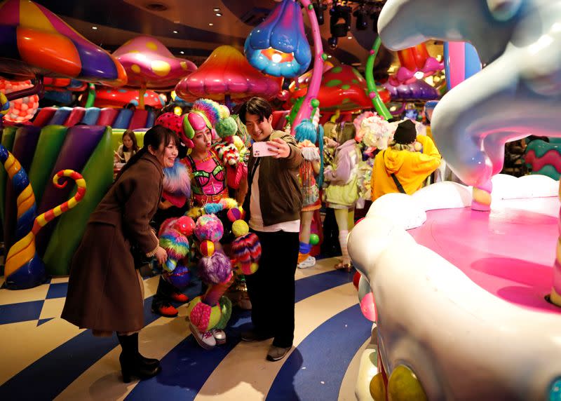 Guests try to take selfie photos with a staff member of 'Monster Girls' at Kawaii Monster Cafe amid the coronavirus disease (COVID-19) outbreak, in Tokyo