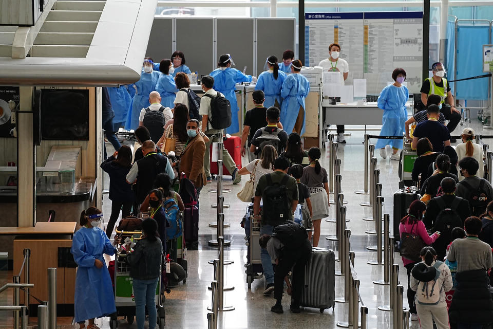 Passengers queue up at the arrival hall for buses going to quarantine hotels from Hong Kong international airport in Hong Kong, Friday, Sep. 23, 2022. Hong Kong’s leader announced the city would no longer require incoming travelers to quarantine in designated hotels as the city seeks to open up globally after nearly two years. The measures will come into effect Monday(AP Photo/Lam Yik)