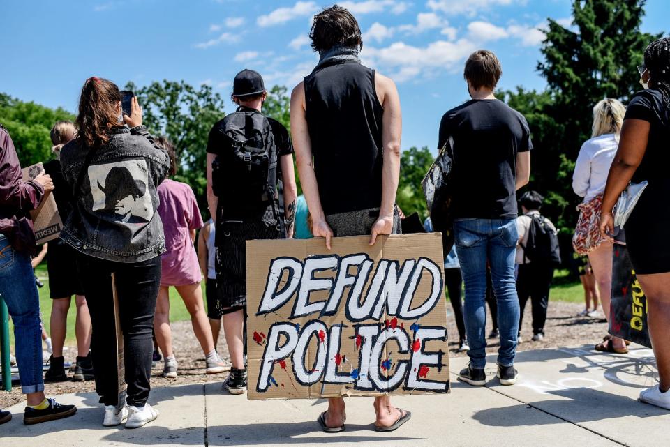 A protester hods a sign reading 'Defund Police' during a demonstration against police brutality and racial injustice on at the rock on the MSU campus on Friday, June 12, 2020, in East Lansing. About 50 people marched from the rock to the East Lansing Police Department were they sat on Abbot Road in protest.