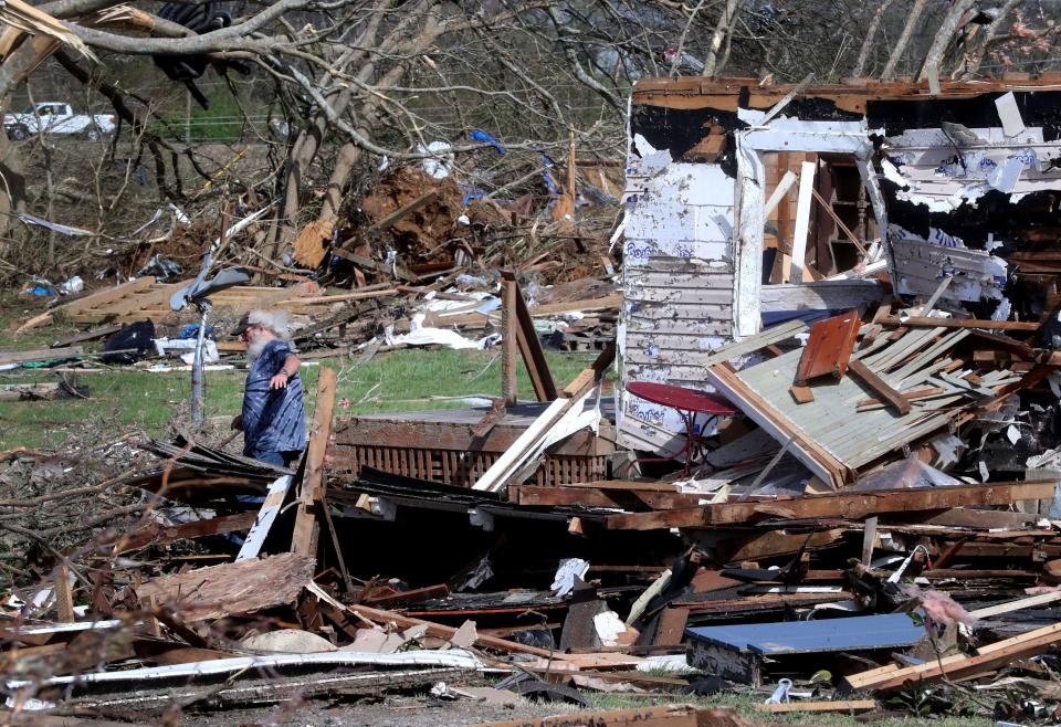 Allen Ambrose cleans up around his home in Readyville on Saturday after an early-morning storm hit his community, destroying property and homes in the early morning hours.