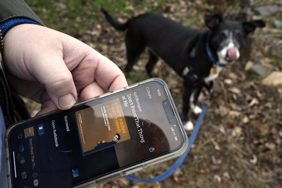 Casey Rosseau prepares to walk his dog Darcy while listening to an e-book in West Hartford, Conn., Feb. 1, 2024. Rosseau, who estimates he reads about 200 books a year, said he'd like to see more regulation of what publishers can charge libraries. Libraries have been grappling with soaring costs of digital titles, both e-books and audio books, that libraries typically lease from publishers for a year or two, with limited usage. (AP Photo/Jessica Hill)