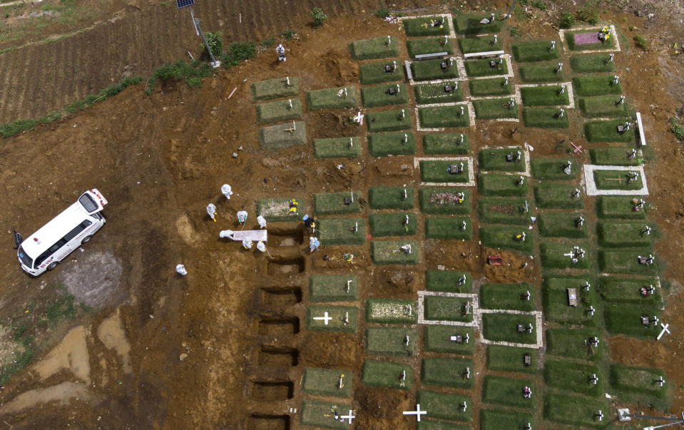 In an aerial view, workers bury a coffin containing the body of a COVID-19 victim at a cemetery reserved for those who died of complications related to coronavirus in Medan, North Sumatra, Indonesia, Sunday, May 2, 2021. (AP Photo/Binsar Bakkara)