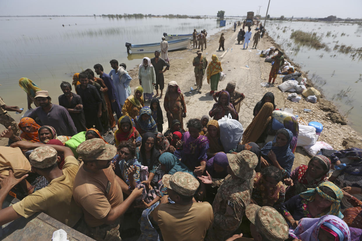 Victims of heavy flooding from monsoon rains wait to receive relief aid from the Pakistani Army in the Qambar Shahdadkot district of Sindh Province, Pakistan, Friday, Sept. 9, 2022. U.N. Secretary-General Antonio Guterres appealed to the world for help for cash-strapped Pakistan after arriving in the country Friday to see the climate-induced devastation from months of deadly record floods. (AP Photo/Fareed Khan)