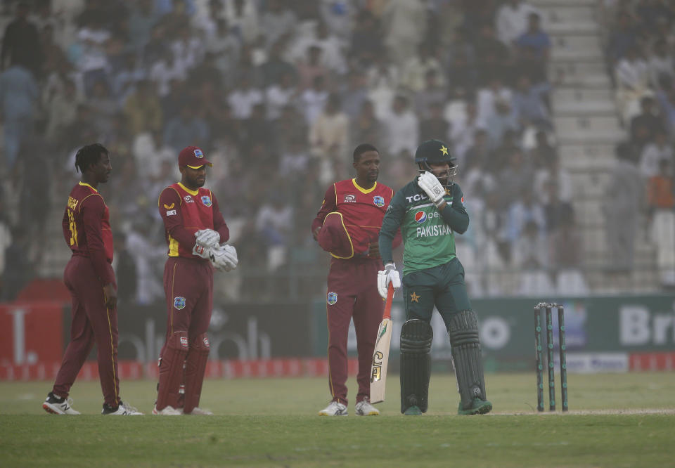 Pakistan's Shadab Khan, right, and West Indies' players cover their face while they leave the filed due to dust-storm stop the play during the third one-day international cricket match between Pakistan and West Indies at the Multan Cricket Stadium, in Multan, Pakistan, Sunday, June 12, 2022. (AP Photo/Anjum Naveed)