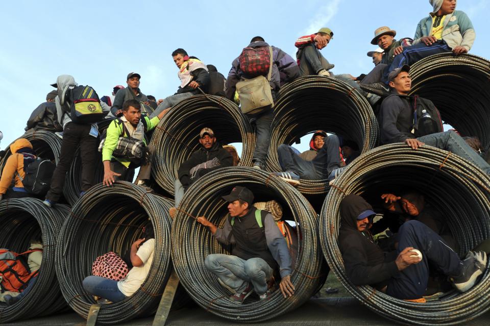 Central American migrants, part of the caravan hoping to reach the U.S. border, get a ride on a truck carrying rolls of steel rebar, in Irapuato, Mexico, Monday, Nov. 12, 2018. Several thousand Central American migrants marked a month on the road Monday as they hitched rides to the western Mexico city of Guadalajara and toward the U.S. border. (AP Photo/Rodrigo Abd)