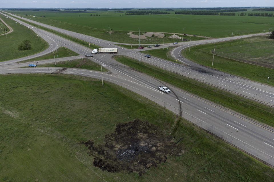 A scorched patch of ground where a bus carrying seniors to a casino ended up after colliding with a semi-trailer truck and burning on Thursday is seen on the edge of the Trans-Canada Highway near Carberry, Manitoba, Friday, June 16, 2023. Police said 15 people were killed and 10 more were sent to hospital. (Darryl Dyck/The Canadian Press via AP)