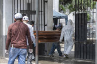 Cemetery workers carry the remains of a person for burial at the General Cemetery in Guayaquil, Ecuador, Monday, April 6, 2020. Guayaquil, a normally bustling city that has become a hot spot in Latin America as the coronavirus pandemic spreads, also has untold numbers dying of unrelated diseases that can’t be treated because hospitals are overwhelmed. (AP Photo/Luis Perez)