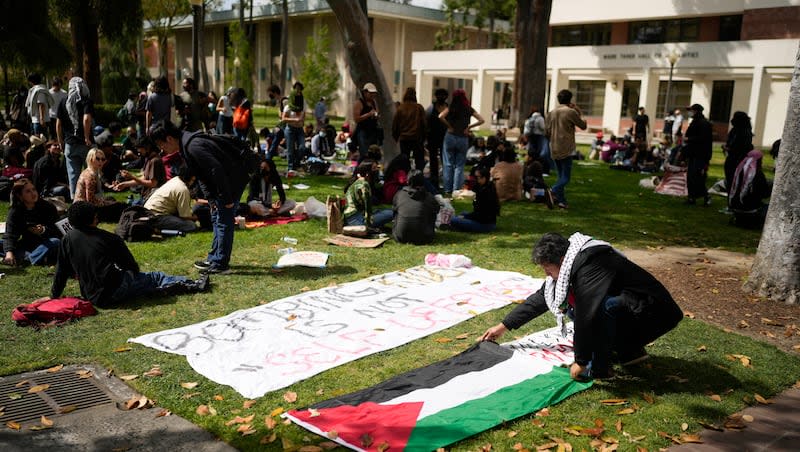 A student places a Palestinian flag on the ground on the USC campus Thursday, April 25, 2024, in Los Angeles.