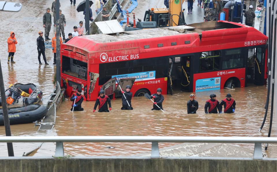 Rescuers search for survivors along a road submerged by floodwaters leading to an underground tunnel in Cheongju, South Korea, Sunday, July 16, 2023. Days of heavy rain triggered flash floods and landslides and destroyed homes, leaving scores of people dead and forcing thousands to evacuate, officials said Sunday. (Kim Ju-hyung/Yonhap via AP)