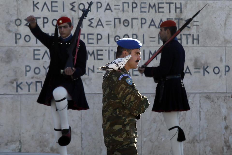 A pigeon sits on the shoulder of a Greek Presidential Guard as his colleagues in traditional Evzones' costumes perform ceremonial duties at the tomb of the unknown soldier in Athens, Wednesday, Oct. 31 2012. Greece's two main labor unions covering civil servants and the private sector have called a 48-hour strike to protest austerity measures due to be voted on next week. The strike call came as the finance minister submitted an amended 2013 budget that raised the country's debt and deficit forecasts for next year. (AP Photo/Kostas Tsironis)