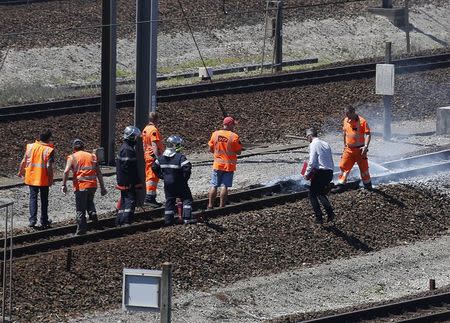 Employees and firemen inspect the tracks after workers operating on the MyFerryLink car and passenger ferry boats set tires into fire at the entrance of the Eurotunnel Channel Tunnel linking Britain and France in Coquelles near Calais, northern France, June 30, 2015. REUTERS/Vincent Kessler