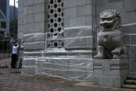 A worker covers the wall after graffiti made by protestors outside Bank of China in Hong Kong, Tuesday, Oct. 15, 2019. A homemade, remote-controlled bomb intended to "kill or to harm" riot control officers was detonated as they deployed against renewed violence in Hong Kong over the weekend, police said Monday, in a further escalation of destructive street battles gripping the business hub. (AP Photo/Vincent Yu)