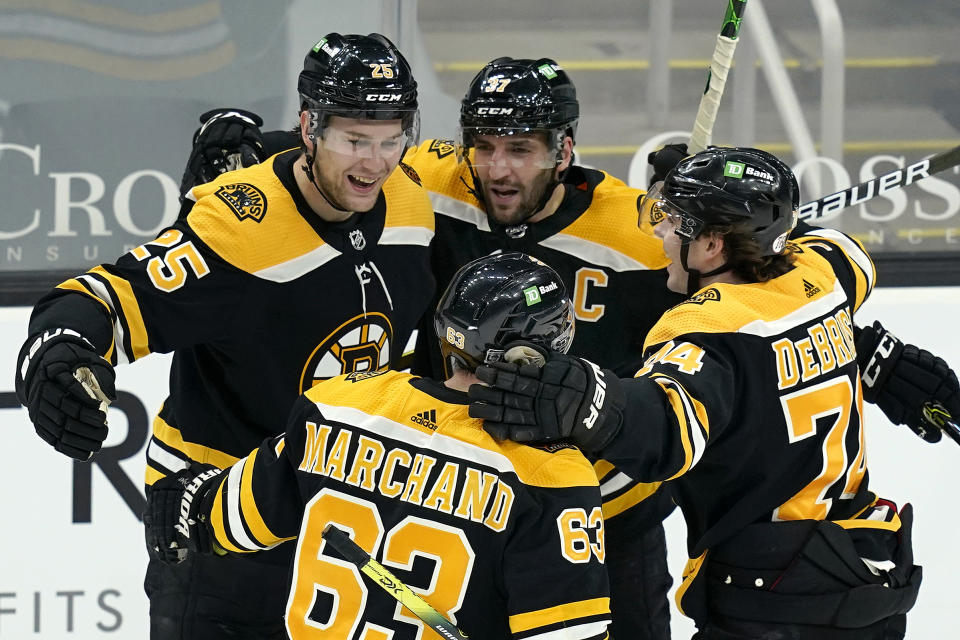 Boston Bruins defenseman Brandon Carlo (25) celebrates his goal with teammates Patrice Bergeron (37), Jake DeBrusk (74), and Brad Marchand (63) in the third period of an NHL hockey game against the Philadelphia Flyers, Thursday, Jan. 21, 2021, in Boston. (AP Photo/Elise Amendola)