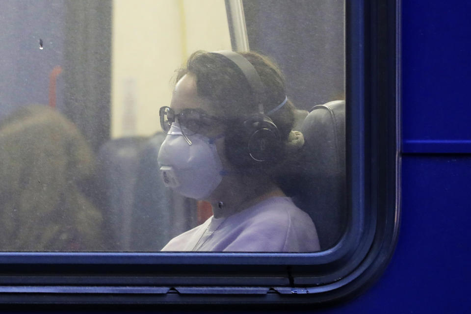 In this March 6, 2020 photo, a woman wears a mask as she rides a bus in downtown Seattle during an evening commute. Expressing alarm both about mounting infections and slow government responses, the World Health Organization declared Wednesday that the global COVID-19 coronavirus crisis is now a pandemic but also said it's not too late for countries to act. (AP Photo/Ted S. Warren)