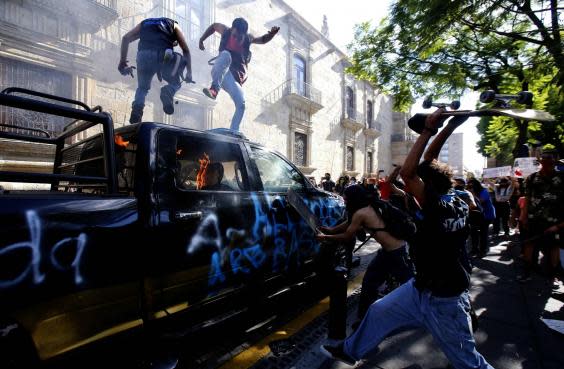 Demonstrators attack a police vehicle during a protest in Guadalajara (AFP via Getty Images)