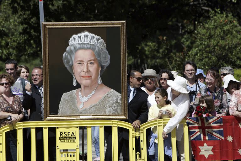 Simpatizantes sostienen un retrato de la reina Isabel II de Gran Bretaña esperando su llegada a Melbourne, Australia, el miércoles 15 de marzo de 2006